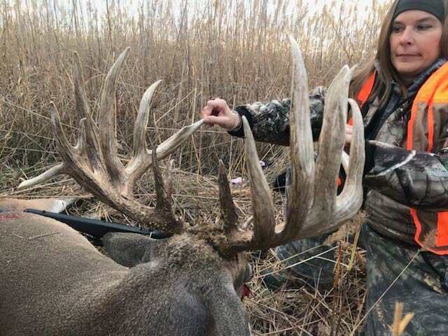 female hunter next to giant buck