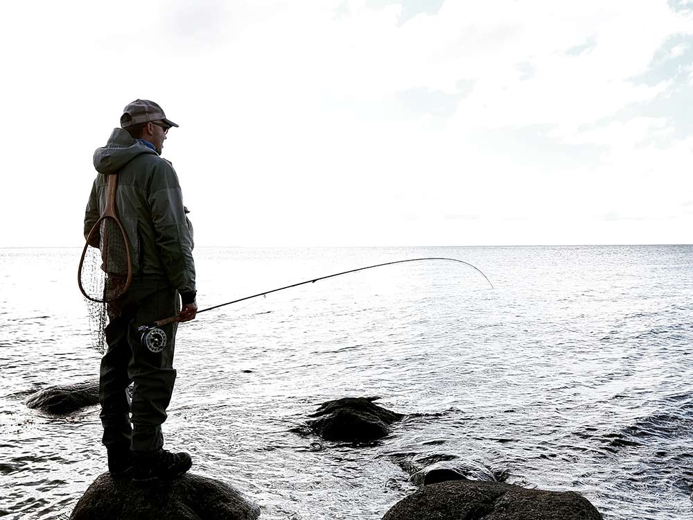 angler standing on rock while fly fishing