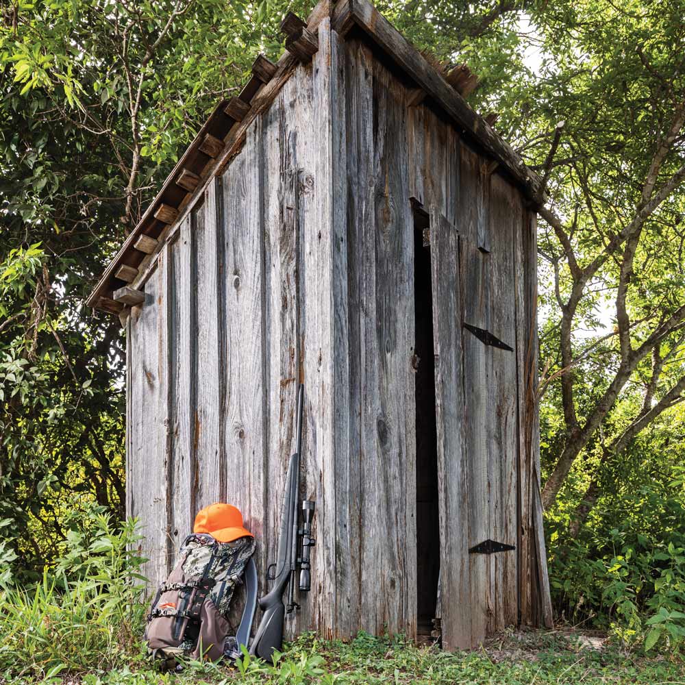 outhouse with hunter gear beside it