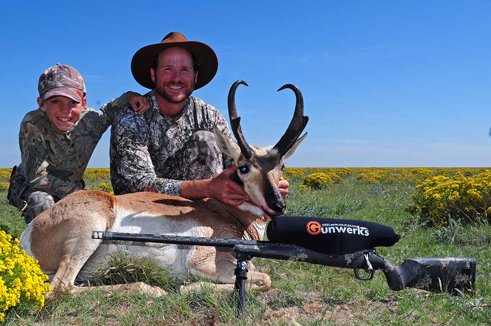 hunter and son kneeling next to an antelope