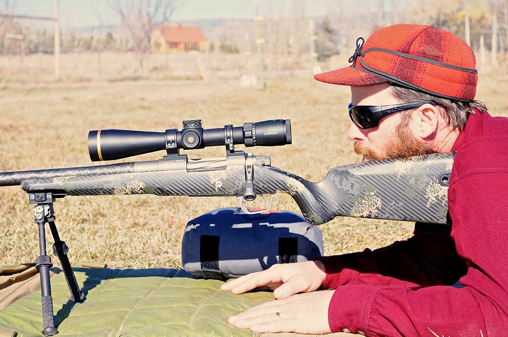 man resting rifle butt stock against shoulder using bipods