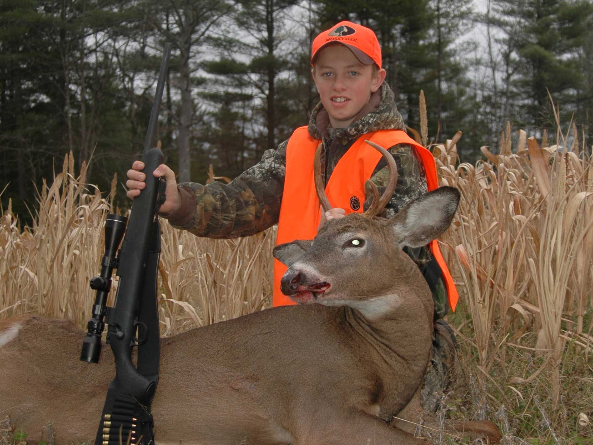 young boy kneeling behind a small deer