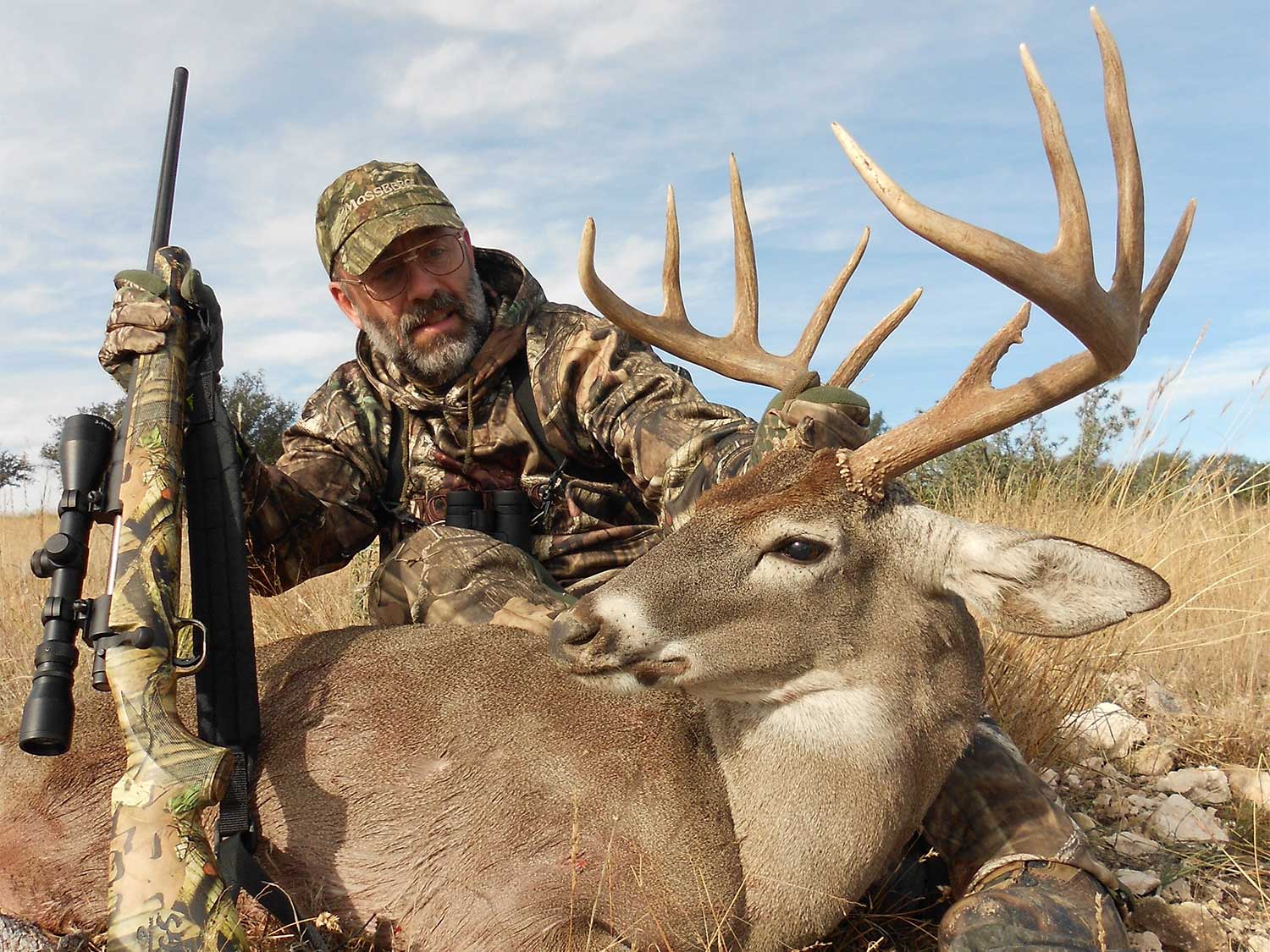 hunter kneeling behind whitetail buck