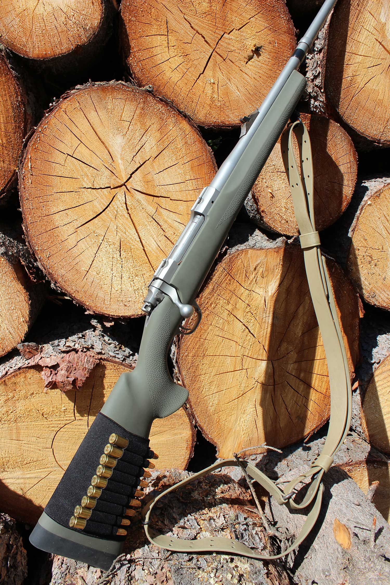 a hunting rifle leaning next to a pile of logs