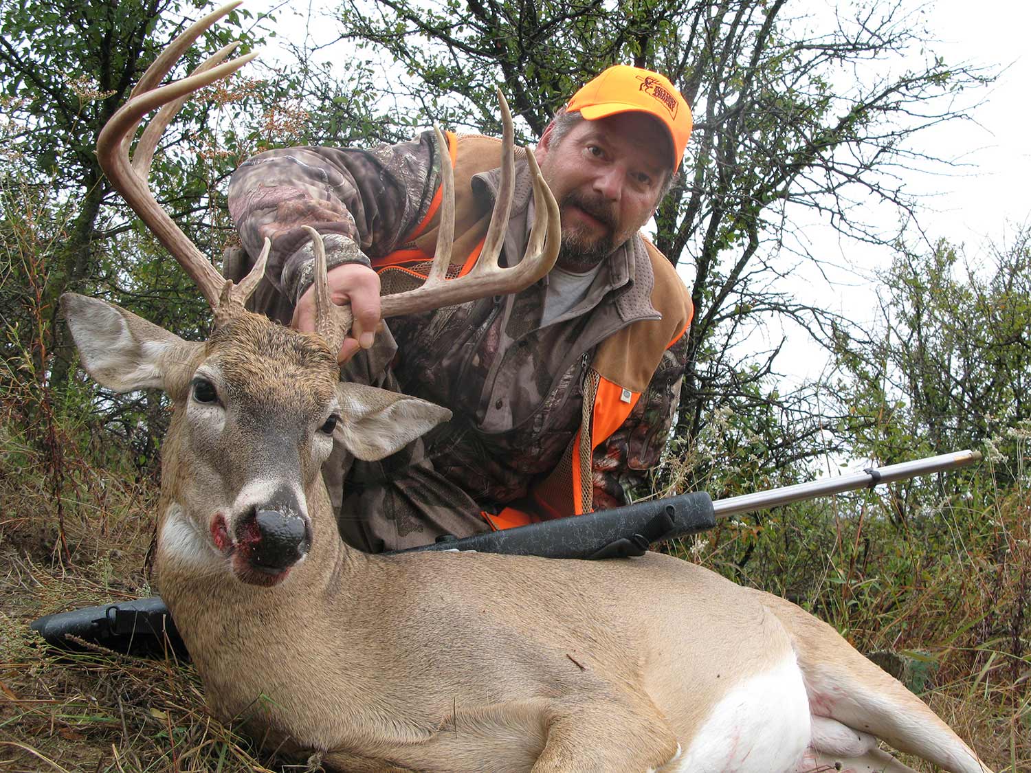 hunter kneeling behind a whitetail buck