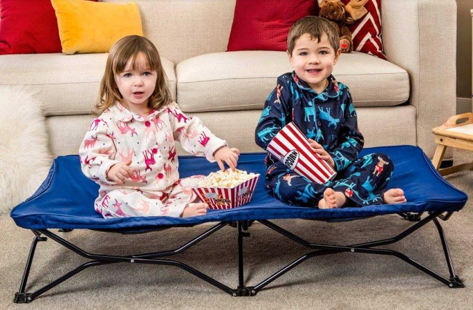  two children sitting on a portable cot