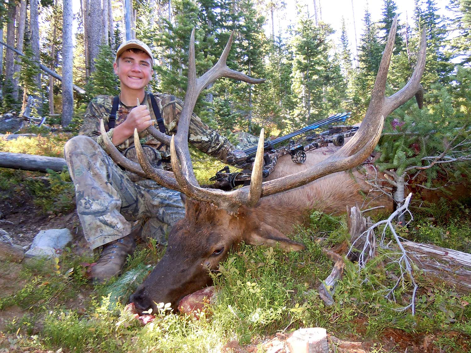 young hunter kneeling beside giant elk