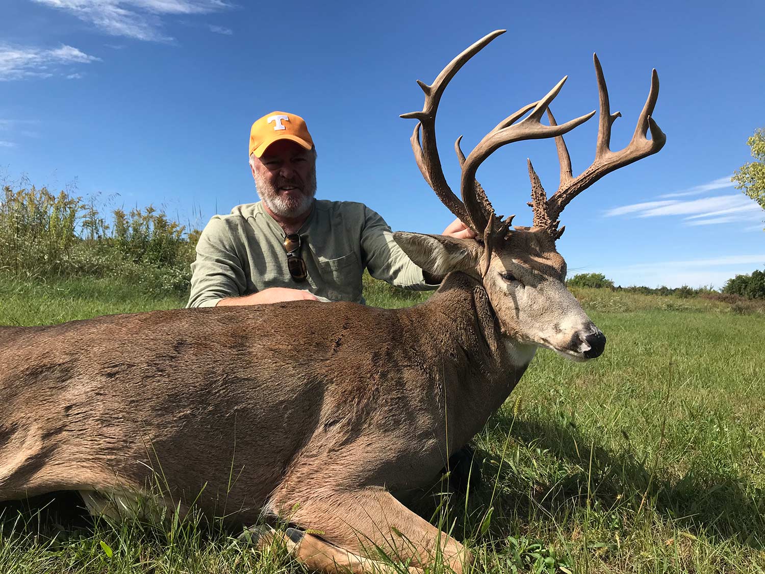 man kneeling behind an early season buck