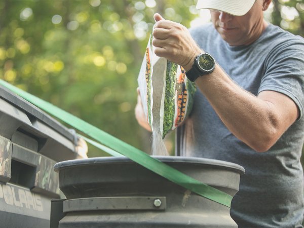 man pouring clover seeds into a seed distributor