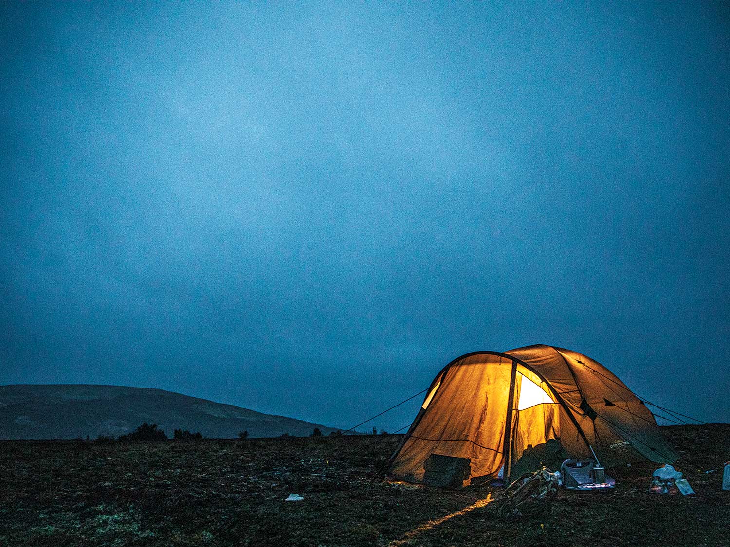 a lit up yellow tent at night in the alaskan wilderness