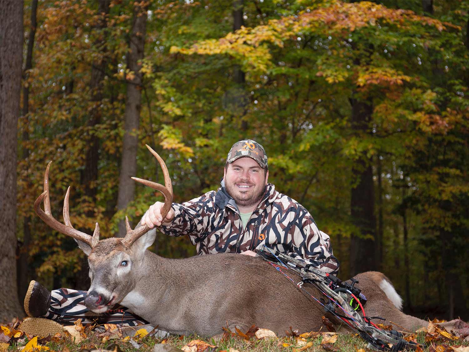 taylor chamberlain kneeling behind a whitetail buck