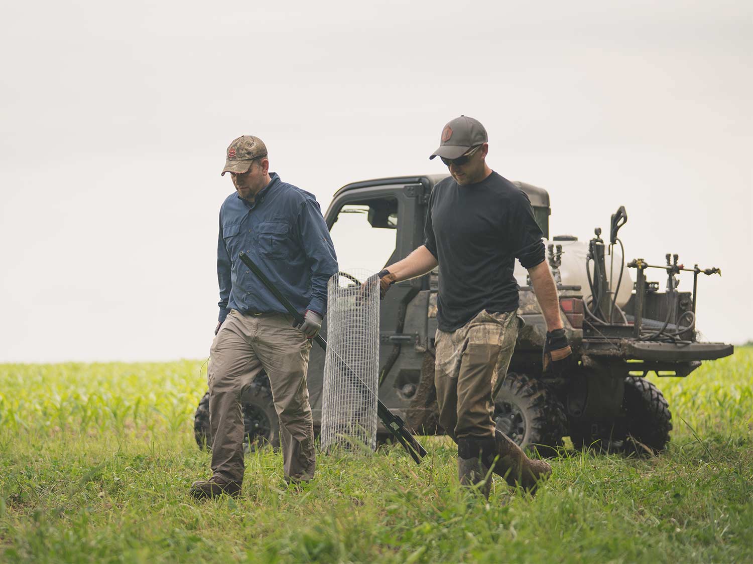 two hunters carrying a wire cage