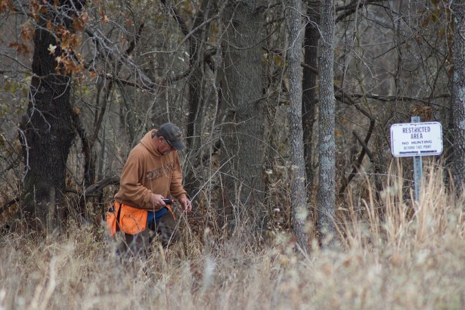 Hunter in a field at a woodline.