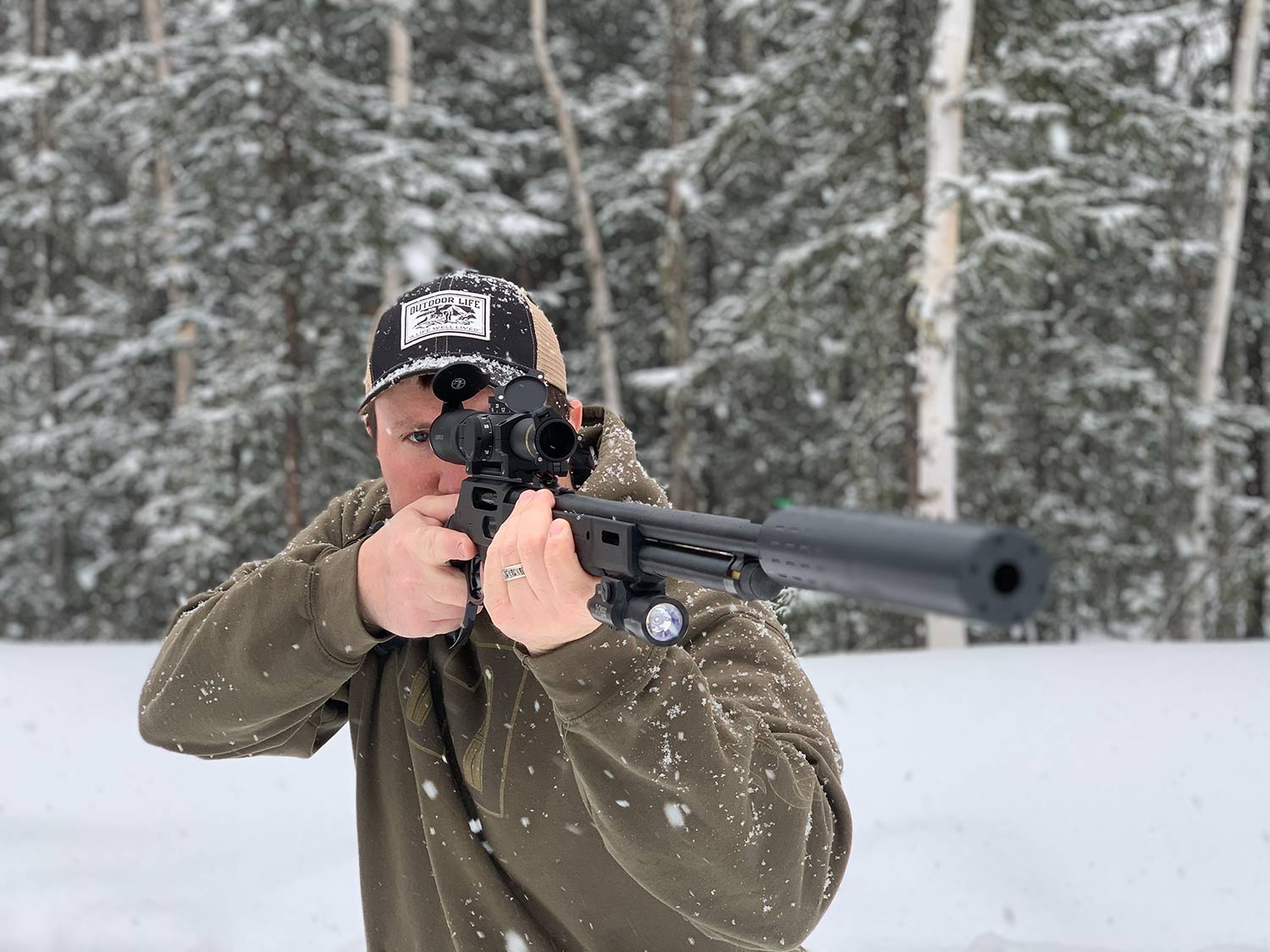 Man aiming a rifle in the snow.