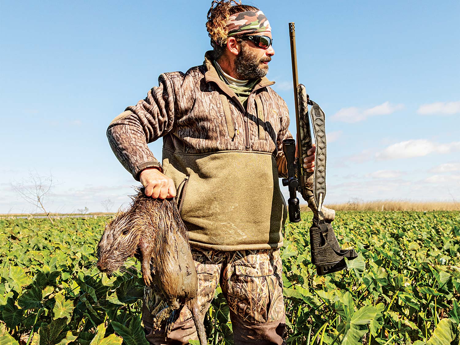 Hunter retrieving a large nutria rat from a swamp.