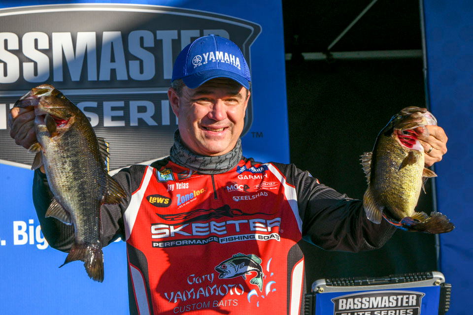 An angler holding up two large bass.