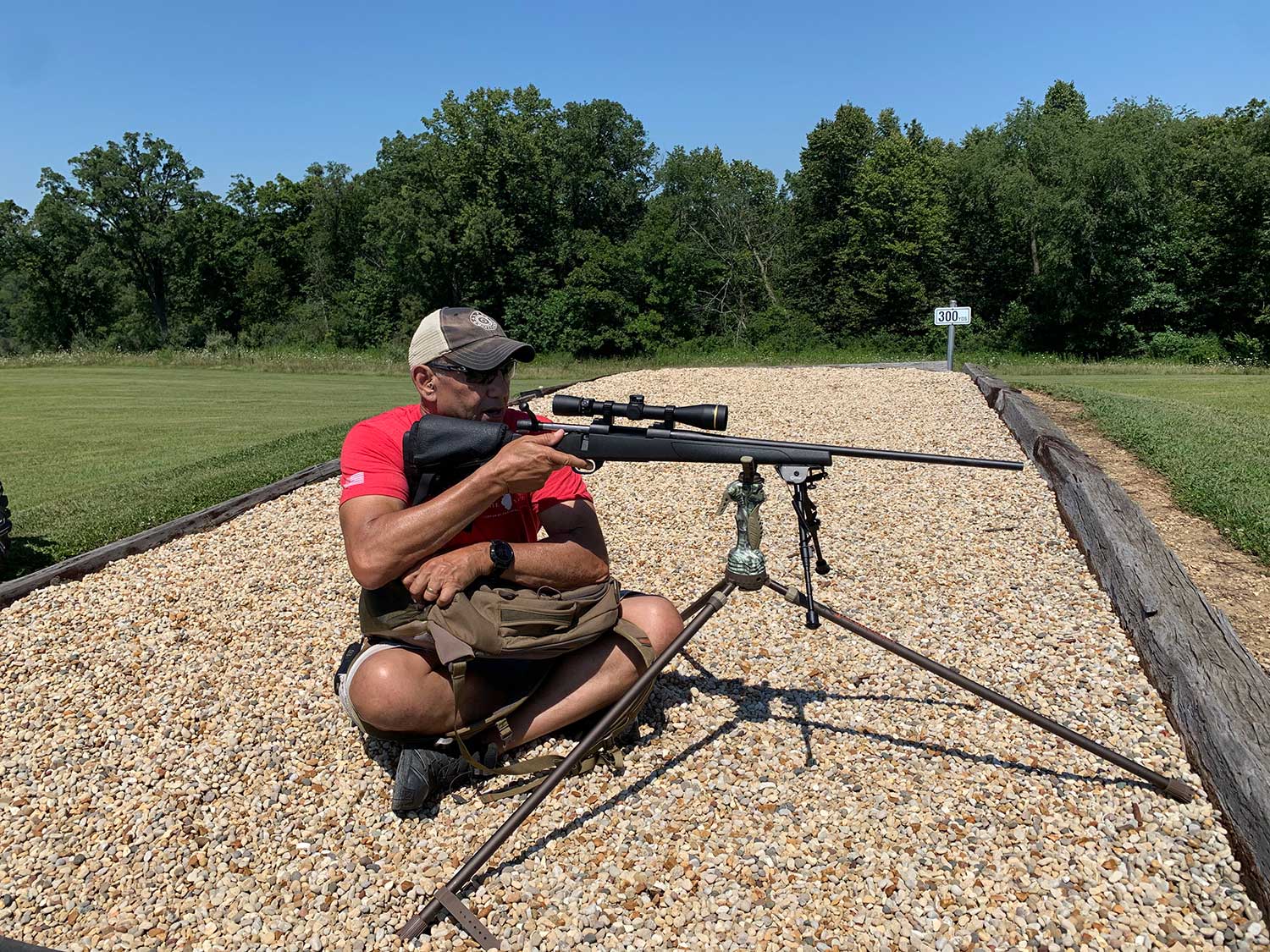 A man aiming a rifle on a shooting stick.