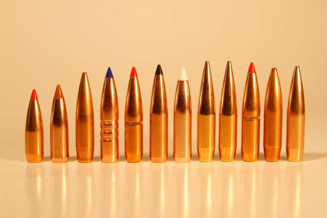 A lineup of several rifle ammunition tips on a table.