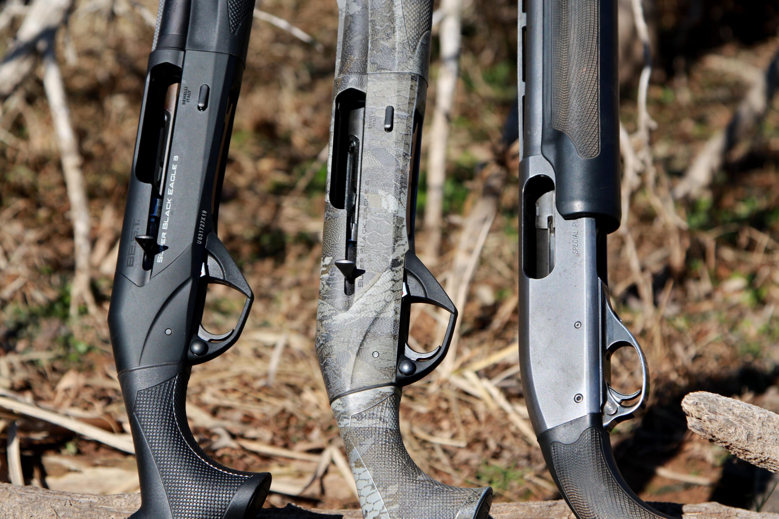 The receivers of three shotguns side by side, with two semi-autos and one pump.