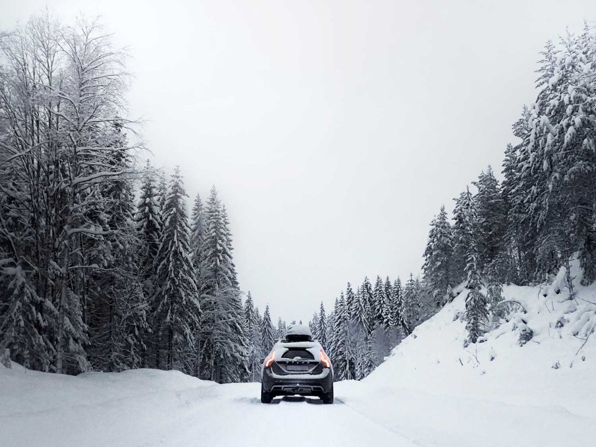 Car in the middle of snowy road using tire chains to drive.