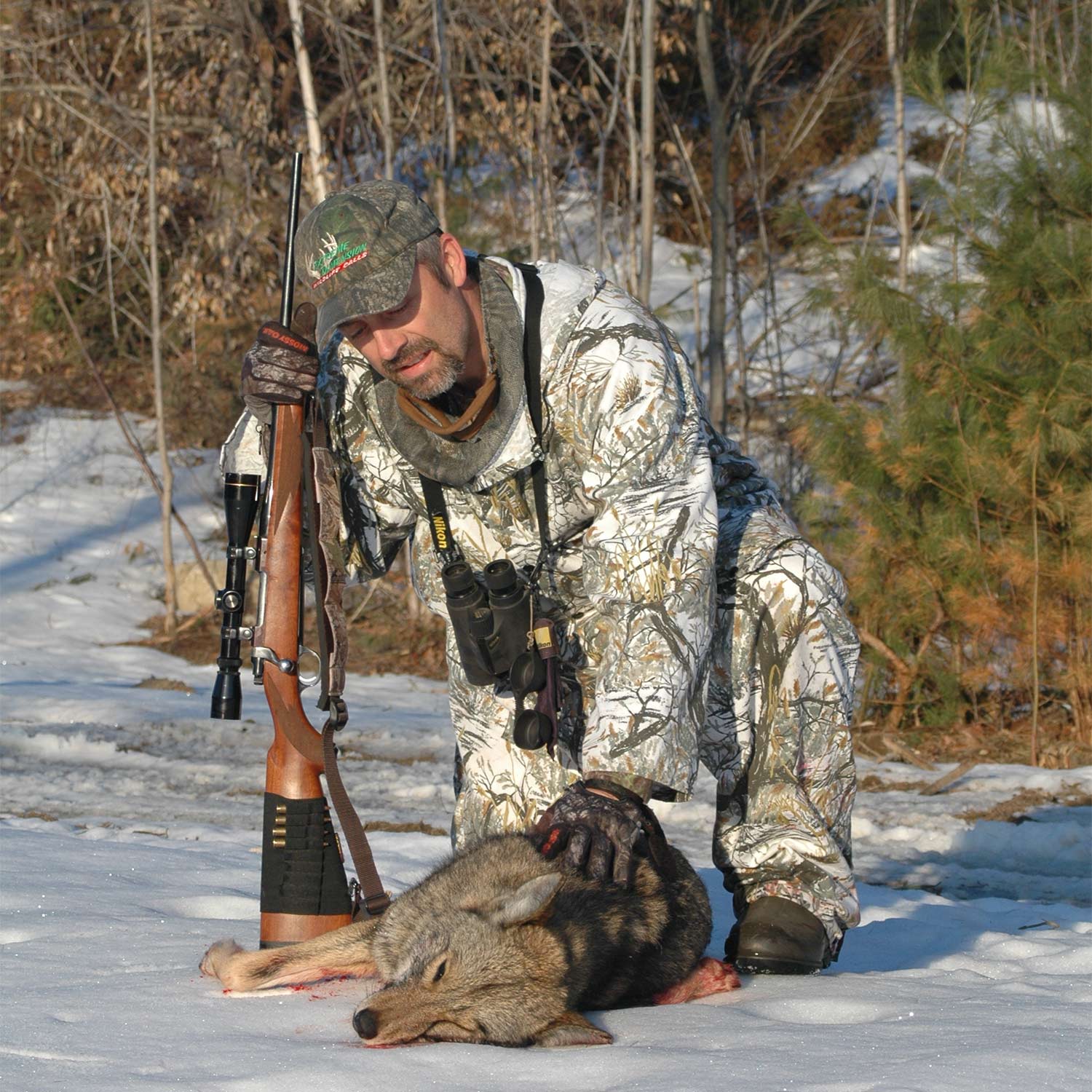 A man stands over a coyote.