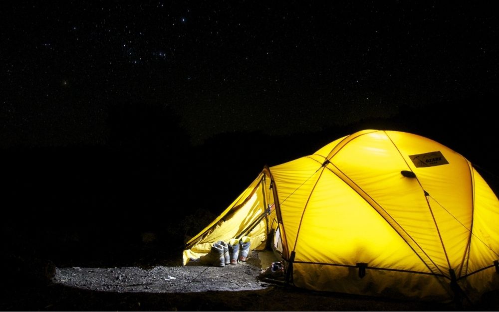 Camping lights light up the interior of a tent.