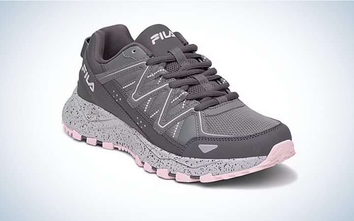  A gray and pink women's hiking shoe on a gray background.