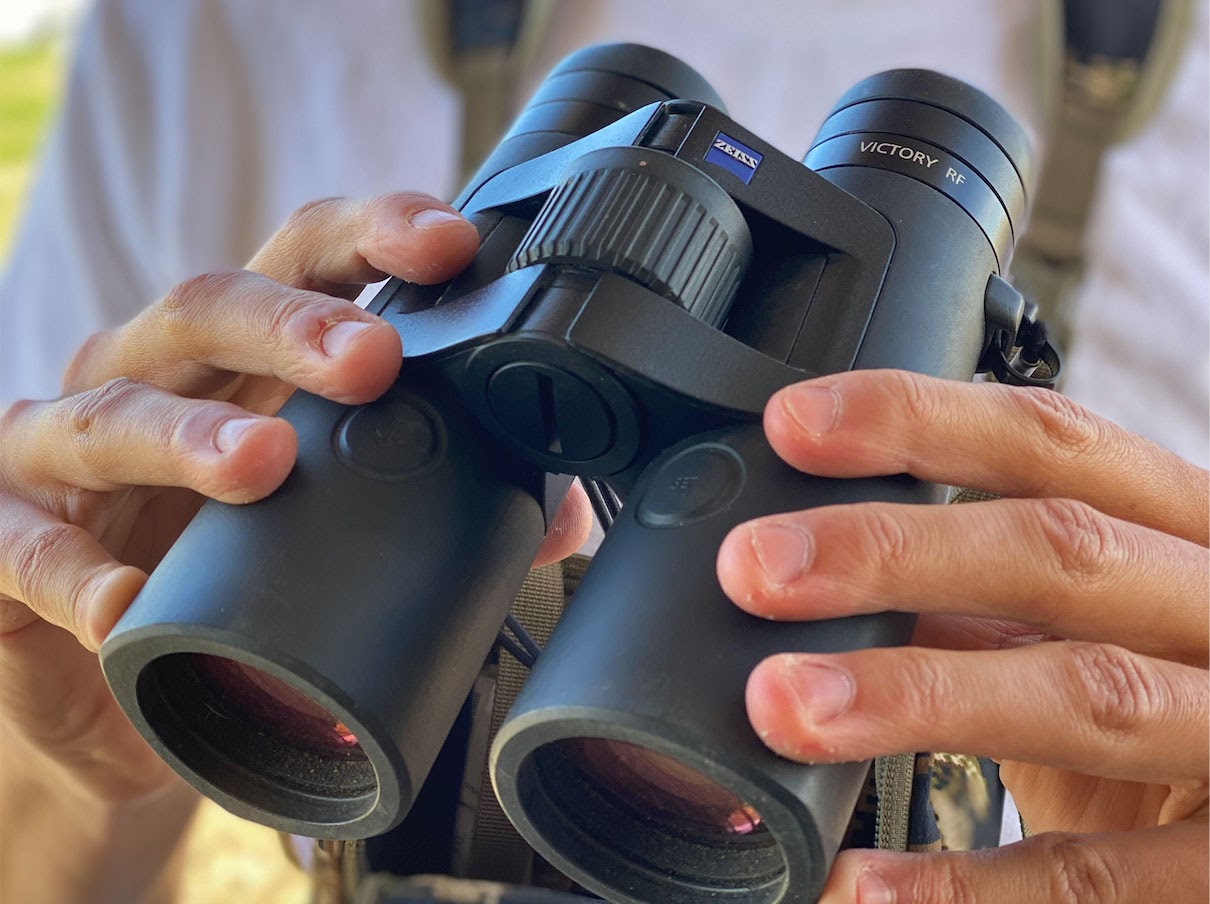 Pair of hands holding black binoculars