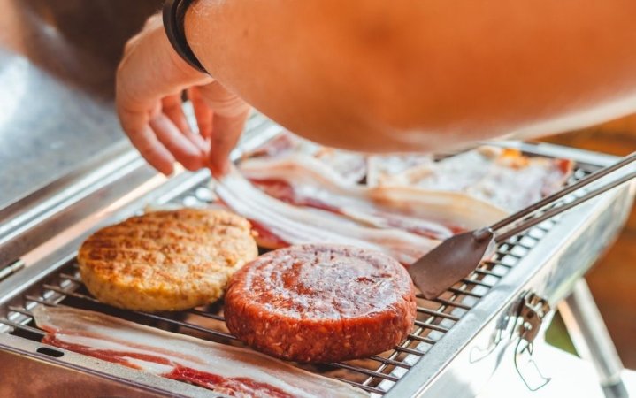 A person who is cooking on a grill different meats for barbecue.