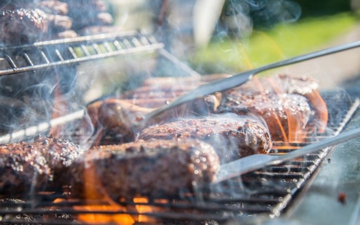 Some meats that are being baked in the silver metal grill of a grill.