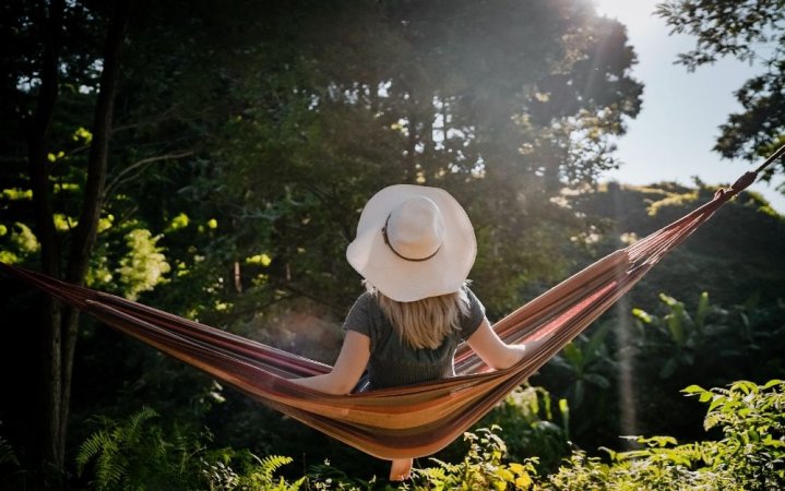 Women on a white hat sitting on a brown hammock