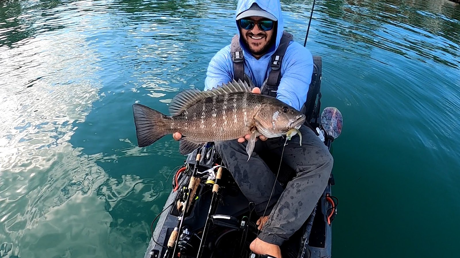 fisherman holding fish in kayak