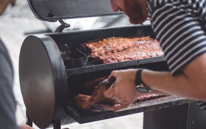 Person putting meat on a smoker