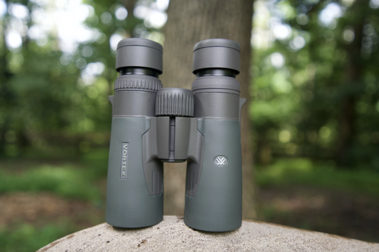 Green binoculars sitting on top of a rock