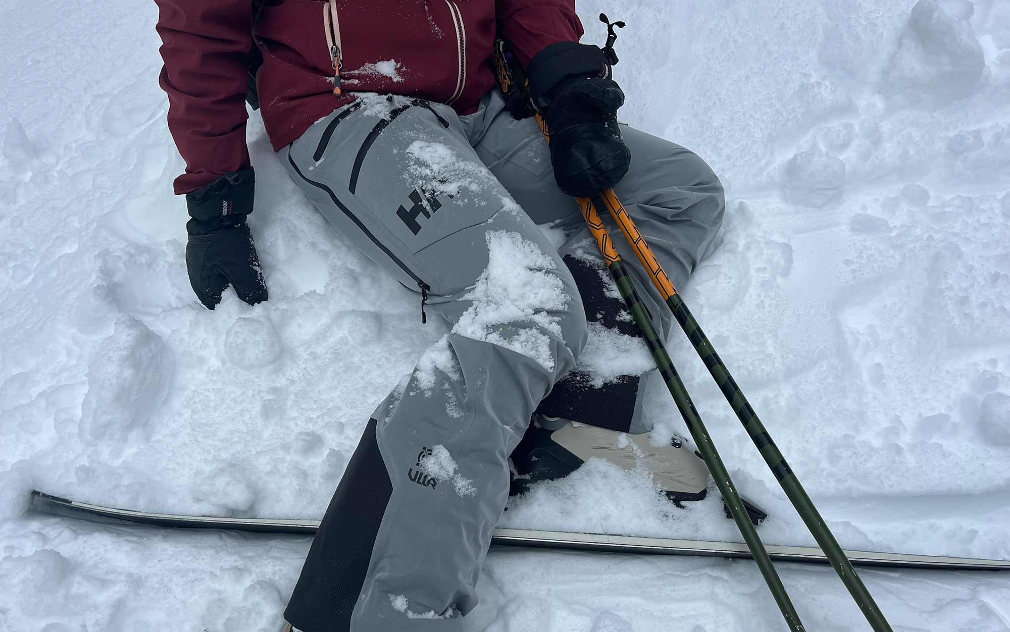 Tester sits in the snow in best snow pants.