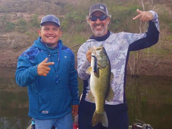 Two men on a river with one holding a large fish