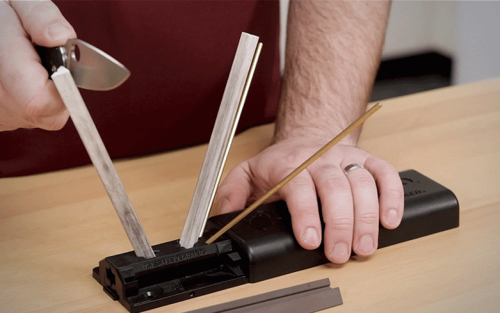  A person sharpening a knife on a black and silver sharpener