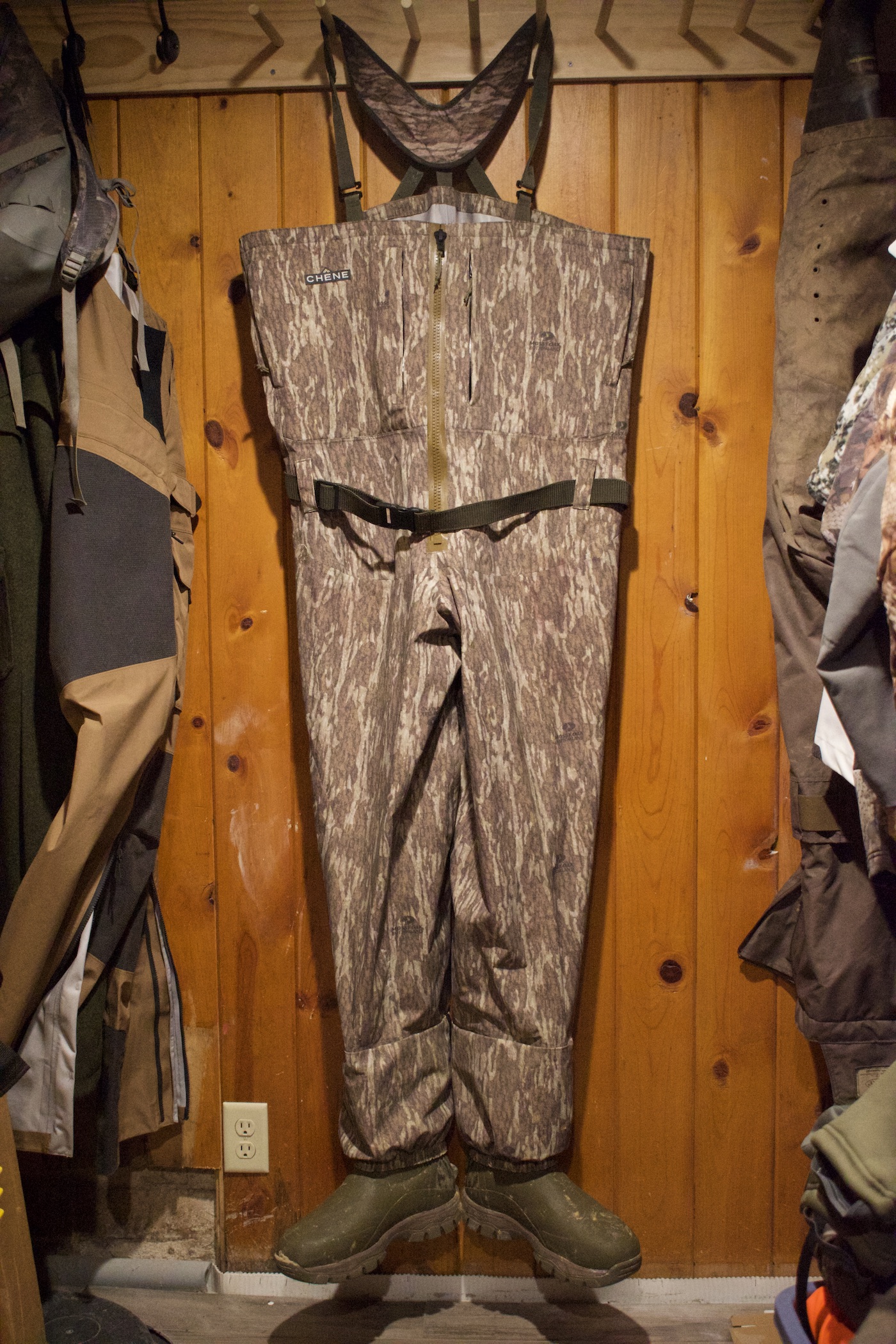 Brown waders hanging against a wood wall