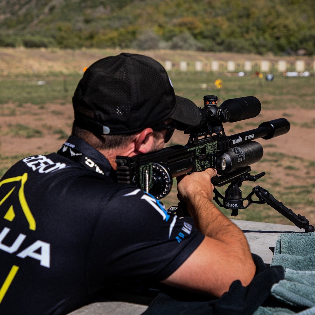 A man shooting a black air rifle