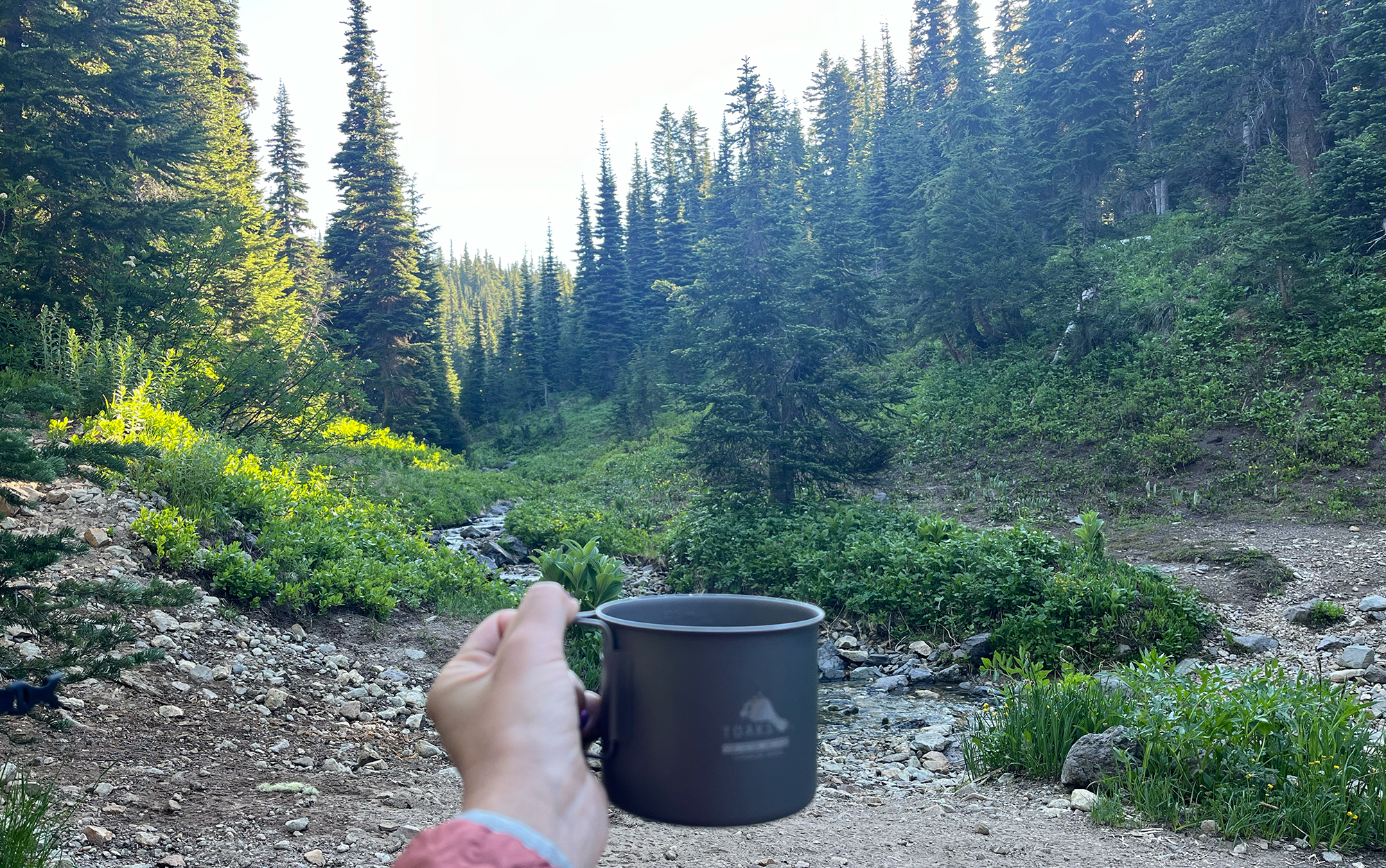 Hiker holds up mug.