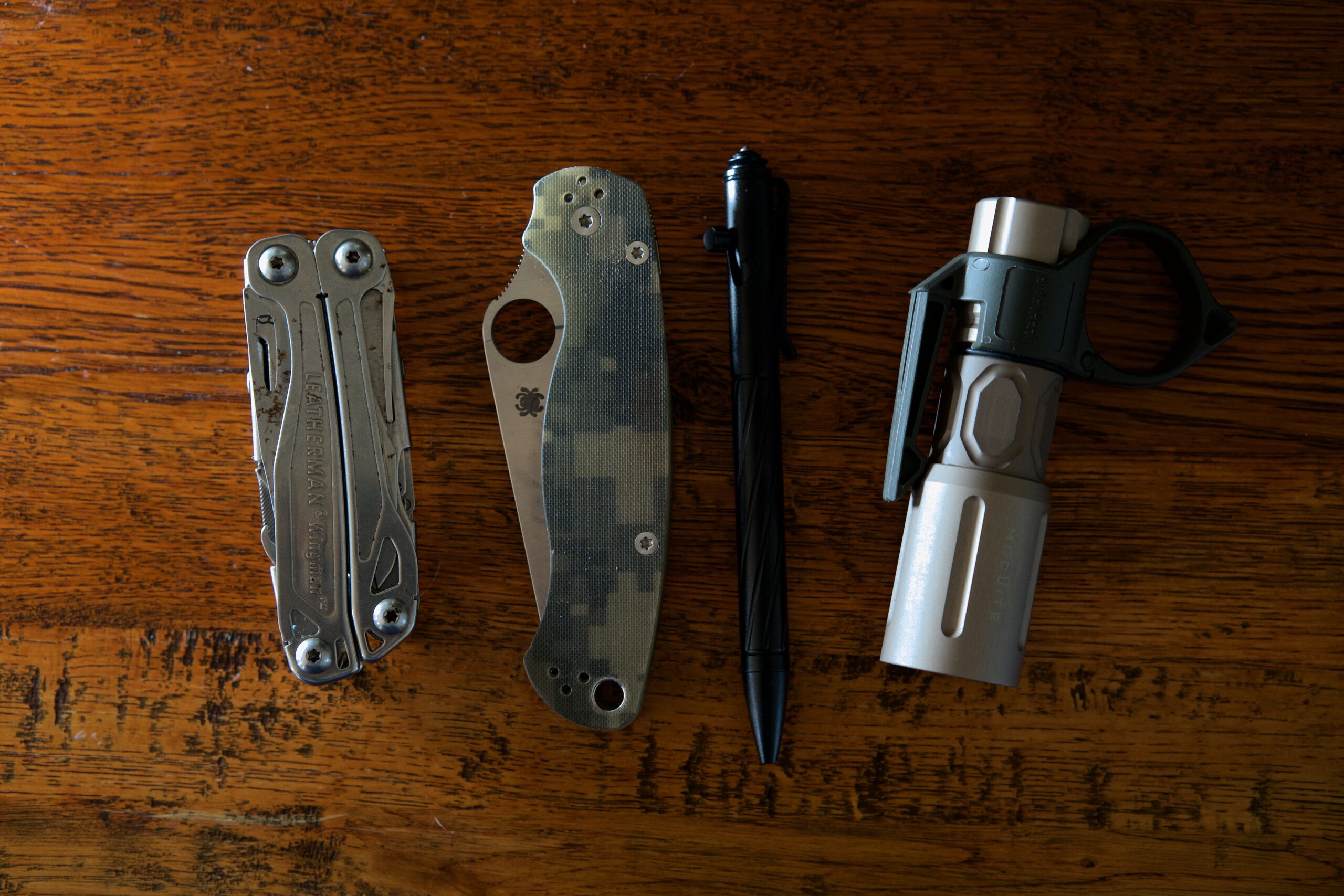 A multi tool, folding knife, pen and flashlight on a table