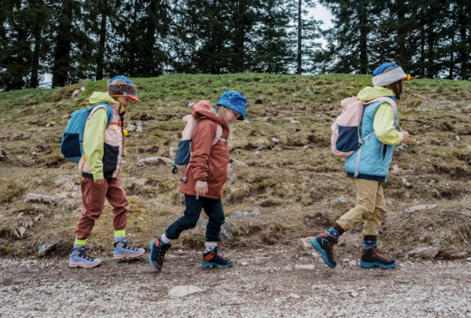  Three kids walking on a path wearing bright jackets