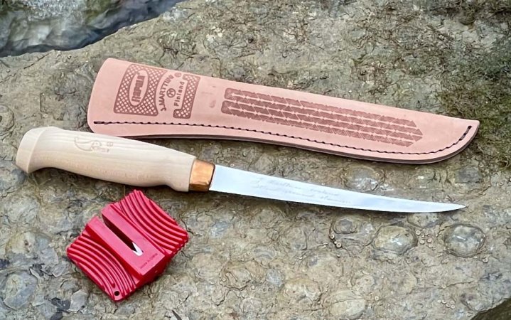  A best fillet knife with a wooden handle next to a leather sheath