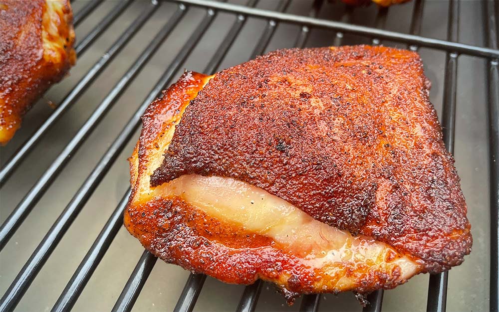 A piece of grilled chicken on a pellet grill grate