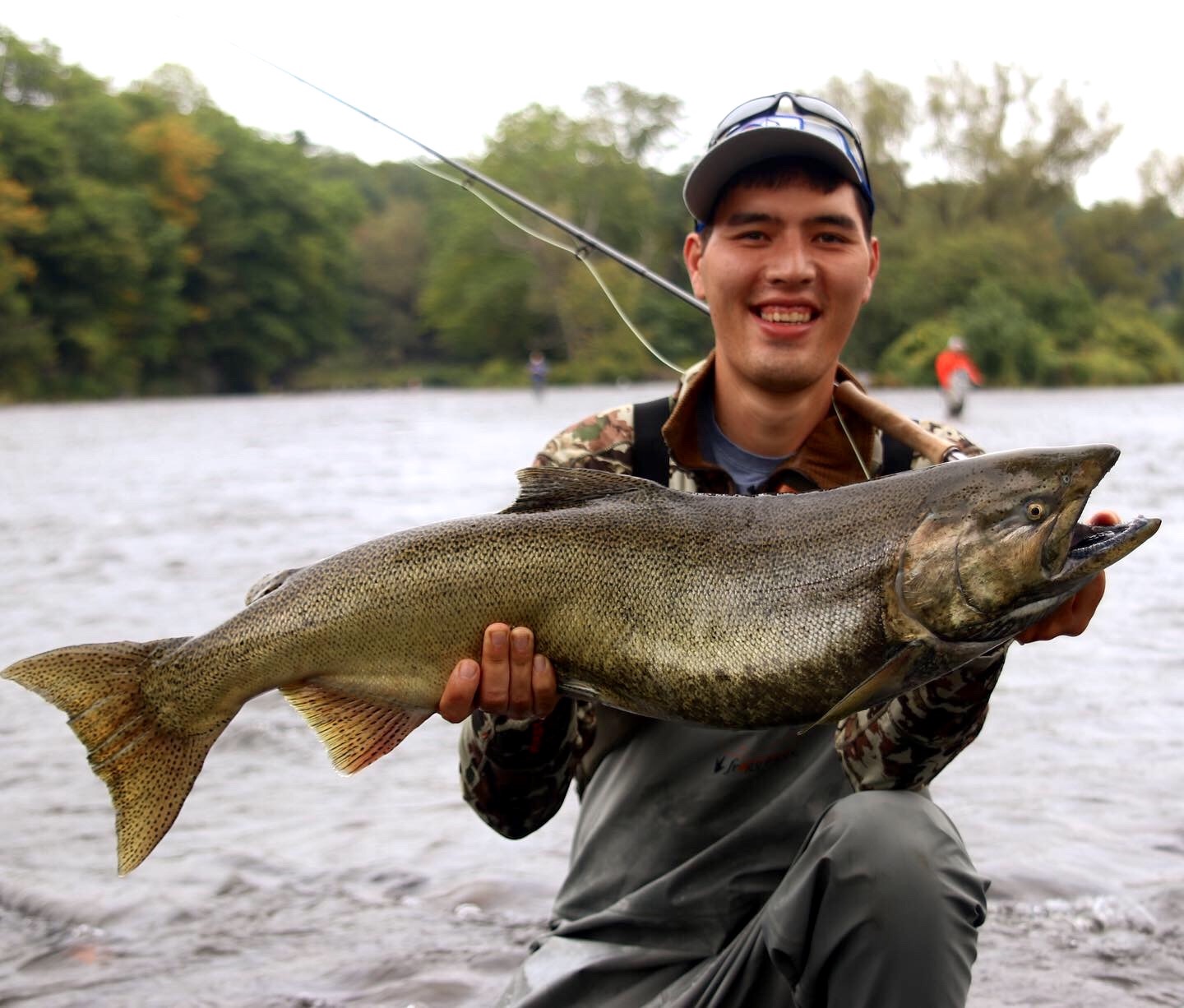 A man in a river holding a fish