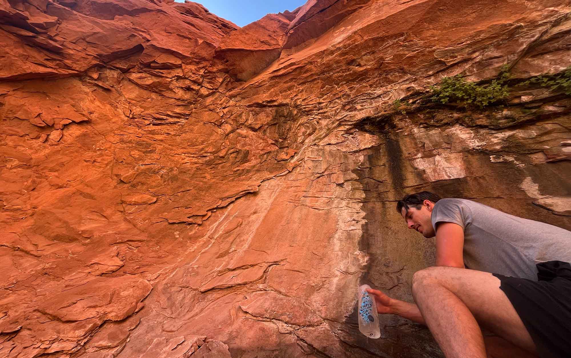 Hiker filters water from desert trickle.