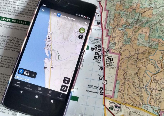 The OnX Backcountry App lying on top of a paper map.