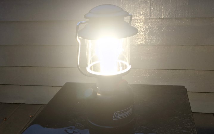  Coleman rechargeable camping lantern on medium sitting on a black table in the rain