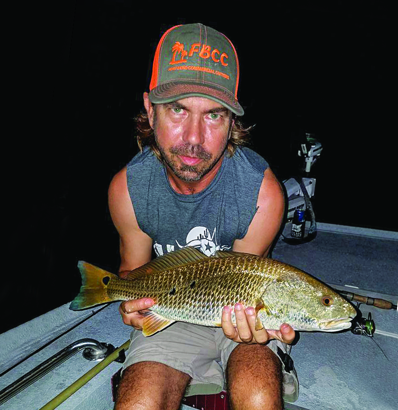 A man holds a redfish.