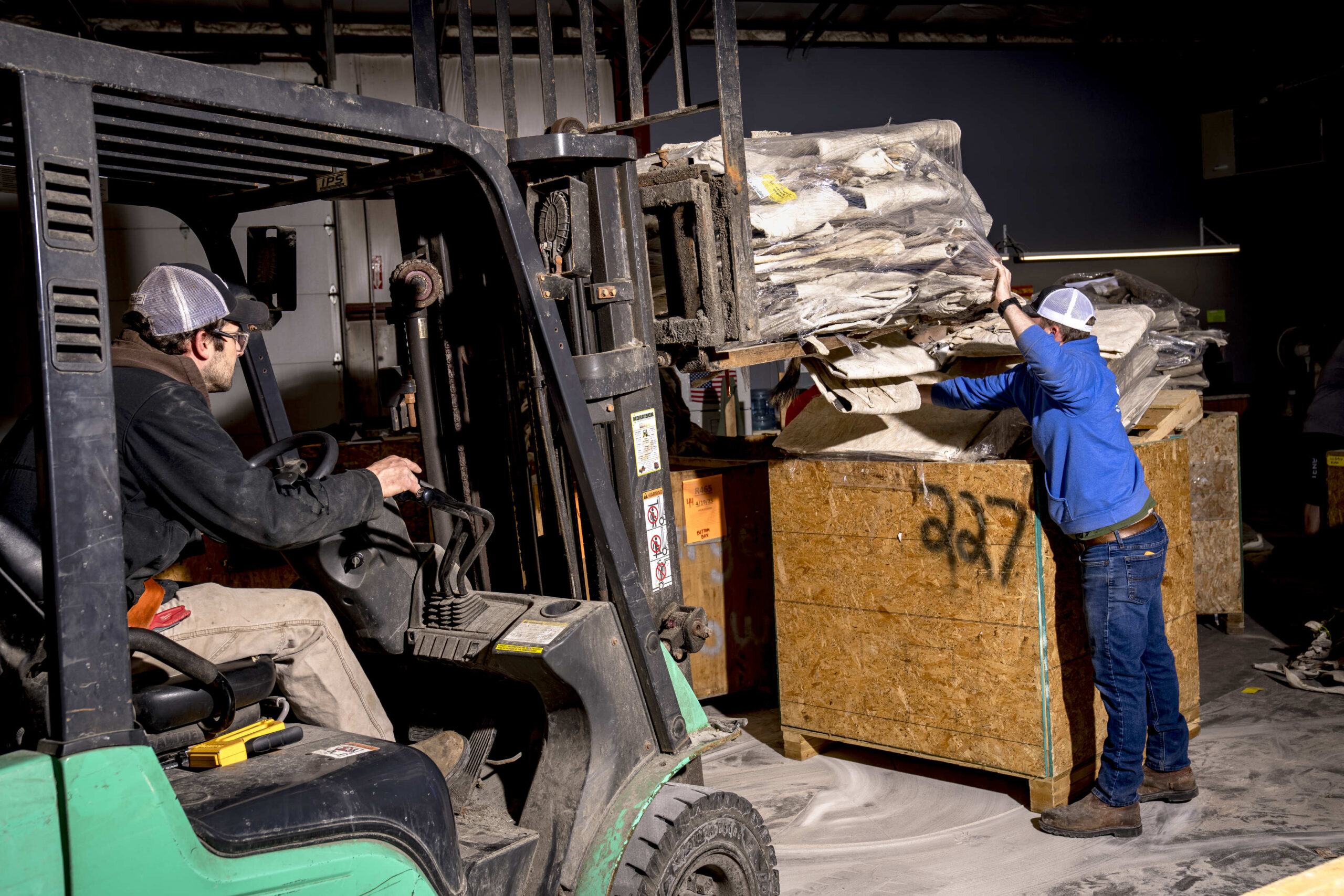 Two tannery employees load hides.